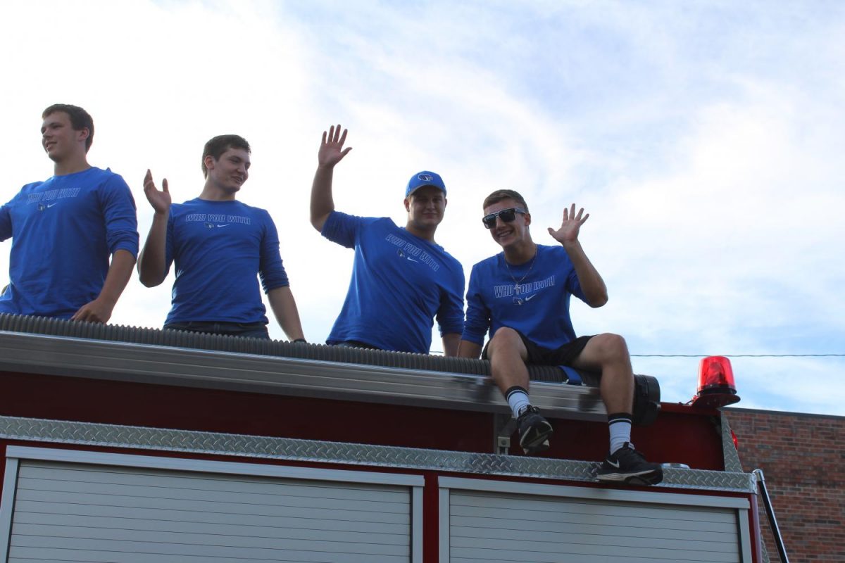 Seniors Cole Mitchell, Grayson Foster, Xaiver Pike, and Kaleb Glore wave to the crowd while sitting on top of the fire truck.